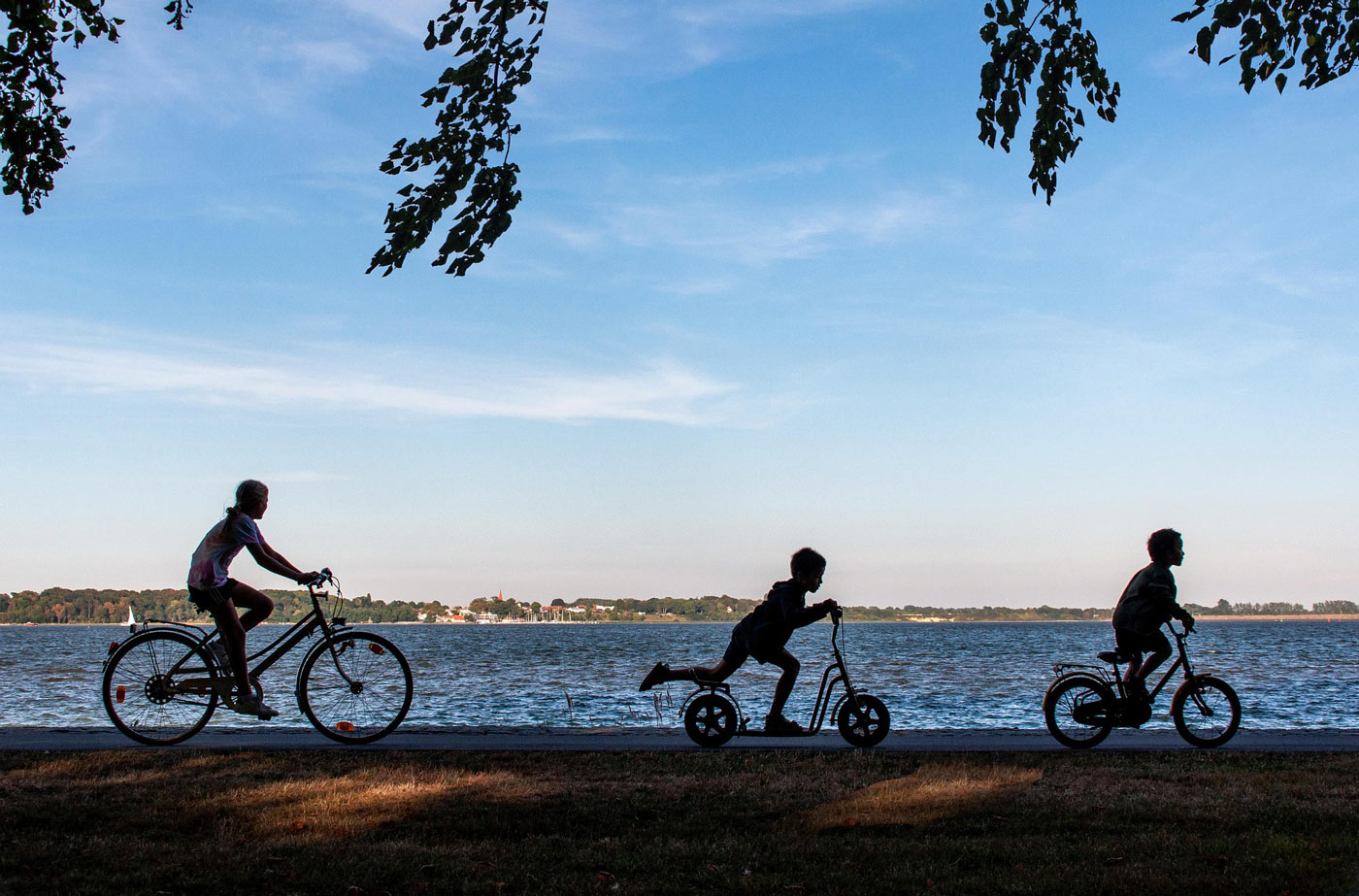 Rodzina na rowerach na promenadzie nad jeziorem, późne popołudnie