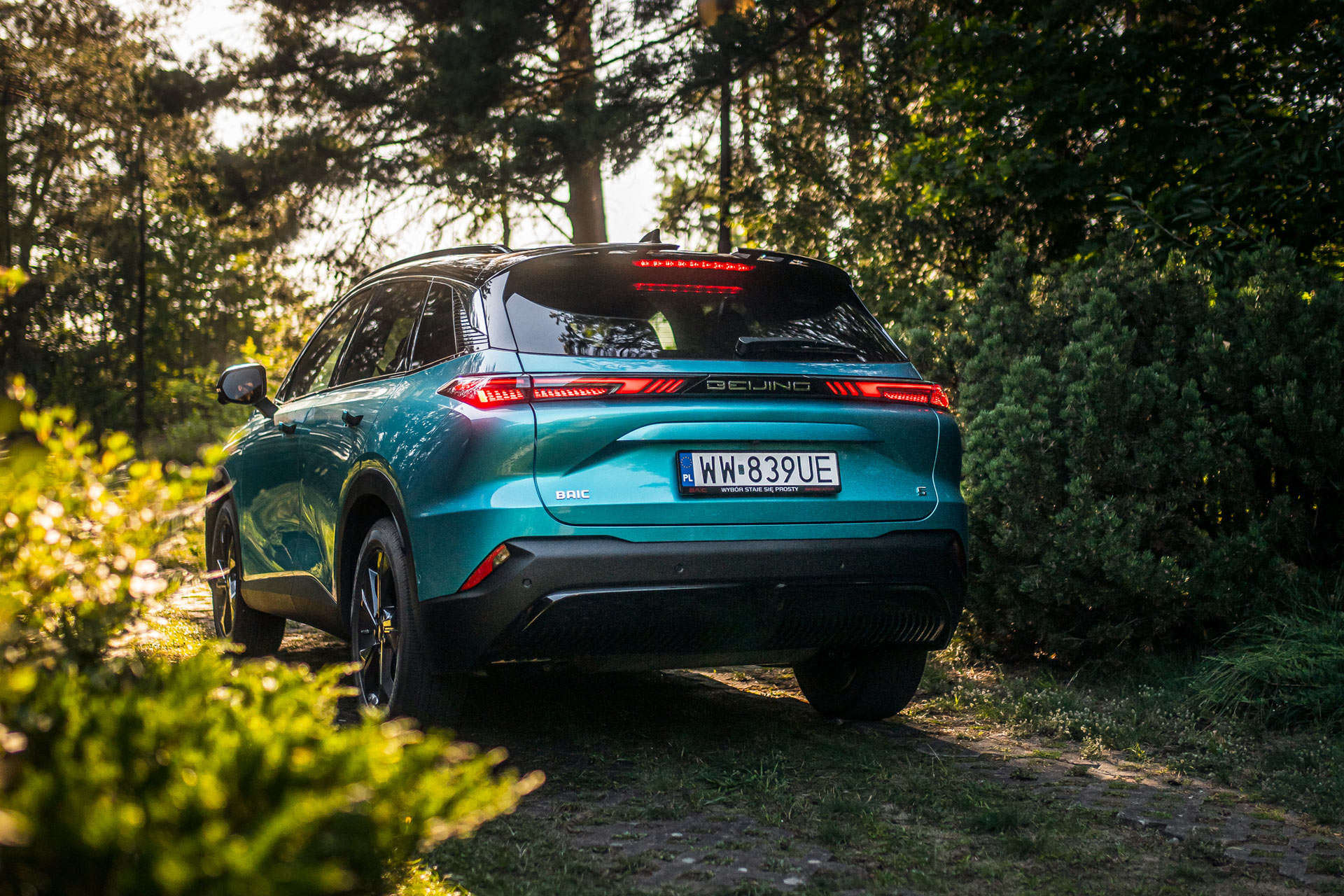 SUV z Chin turkusowy metalizowany, las, nawierzchnia z płyt ażurowych