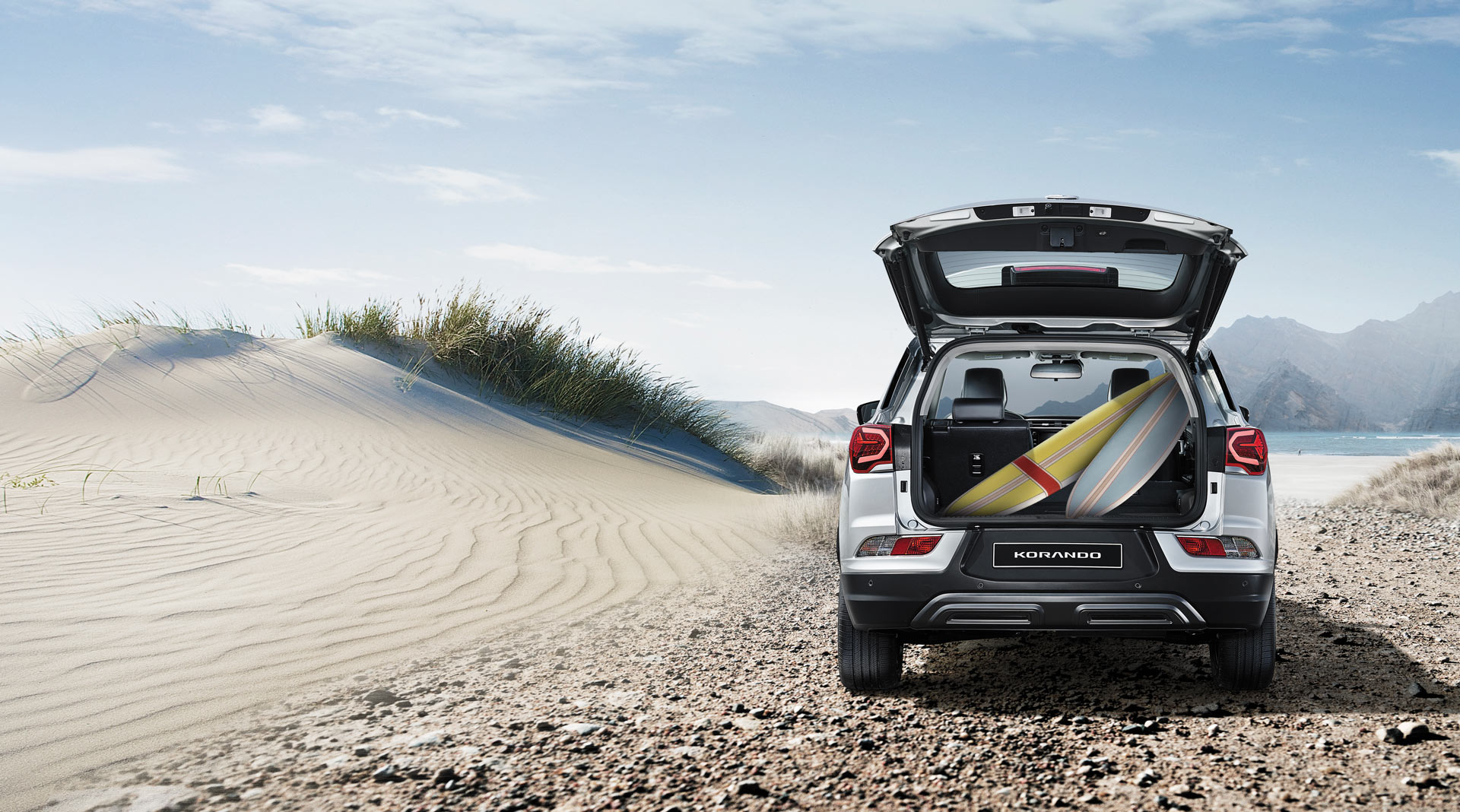 Bagażnik Korando zapakowany surfboardem. Samochód Sports Utility Vehicle na wydmie, piasek