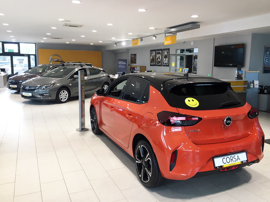 Wnętrze salonu Opel. Pomarańczowa Corsa F, Astra V hatchback