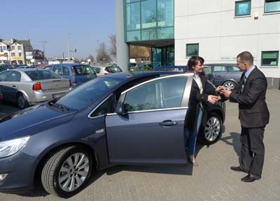 Doradca serwisowy odprowadza panią Agnieszkę do samochodu, dziękuje jej za wizytę w serwisie Opel i żegna się z nią.