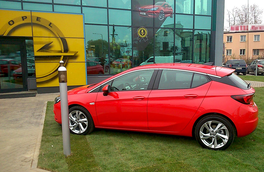 Nowy, czerwony Opel przed wyremontowanym salonem